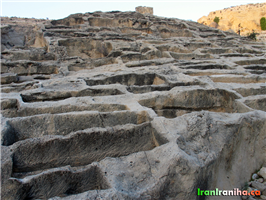  نمای  نزدیک  از  کوه  یکپارچه  سنگی  که  درون  آن  حفره‌های  متعدد  کنده‌شده  است. 